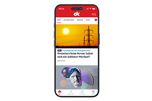 Smartphone mit geöffneter DK-App zeigt Artikel zu Strompreisen und Gesundheitsthemen auf dem Startbildschirm.  